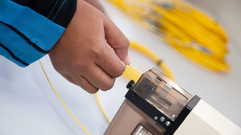 Technician performing fiber optic installation with fiber optic cable.