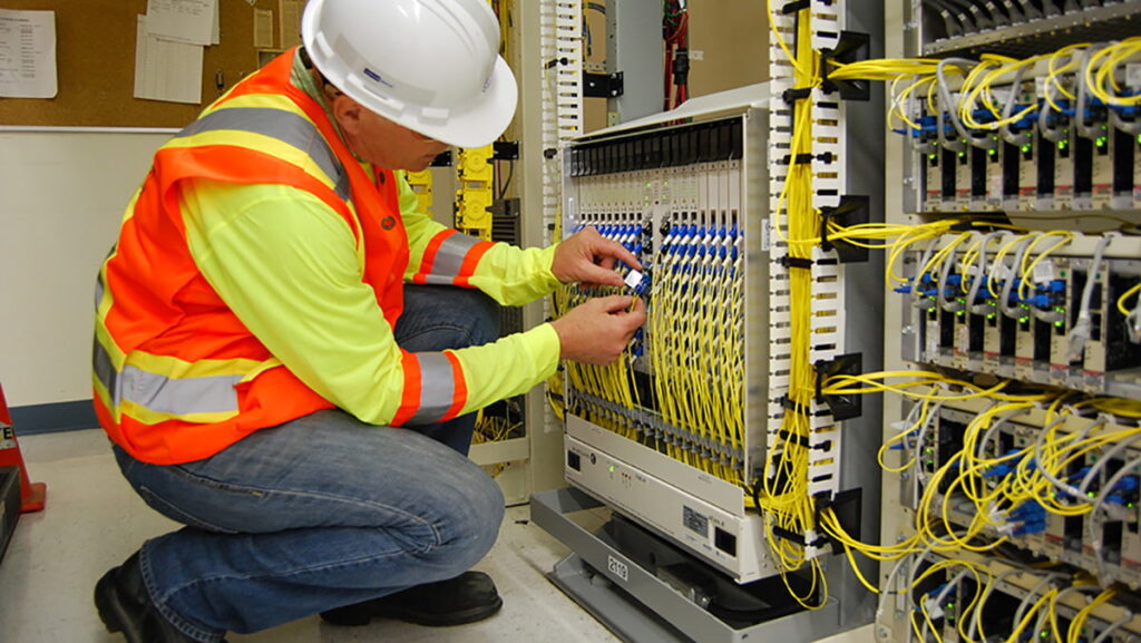 Technician installing fiber optic cabling in a network cabinet