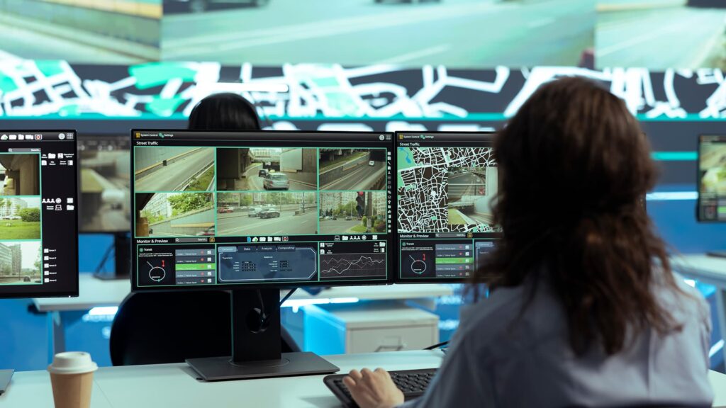 Operator monitoring live CCTV traffic camera feeds on multiple control room screens