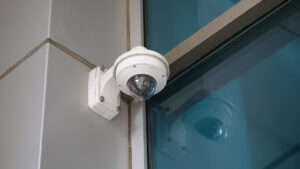 CCTV security camera installed on a wall near a glass door for business security
